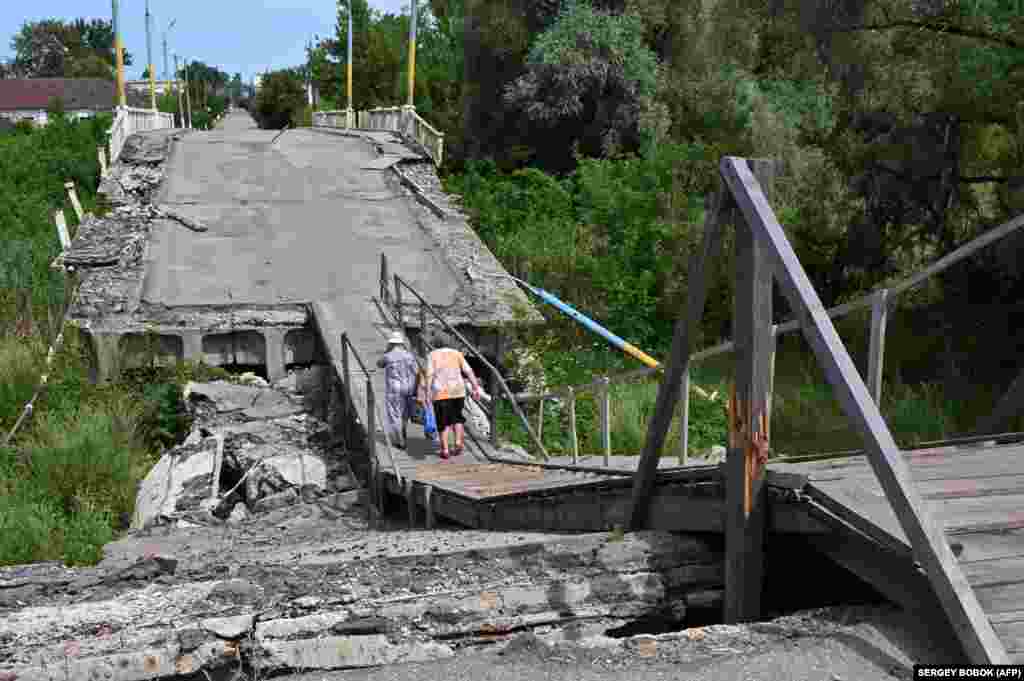 People walk on a destroyed bridge over the Vovcha River in Vovchansk in Ukraine&#39;s Kharkiv region.