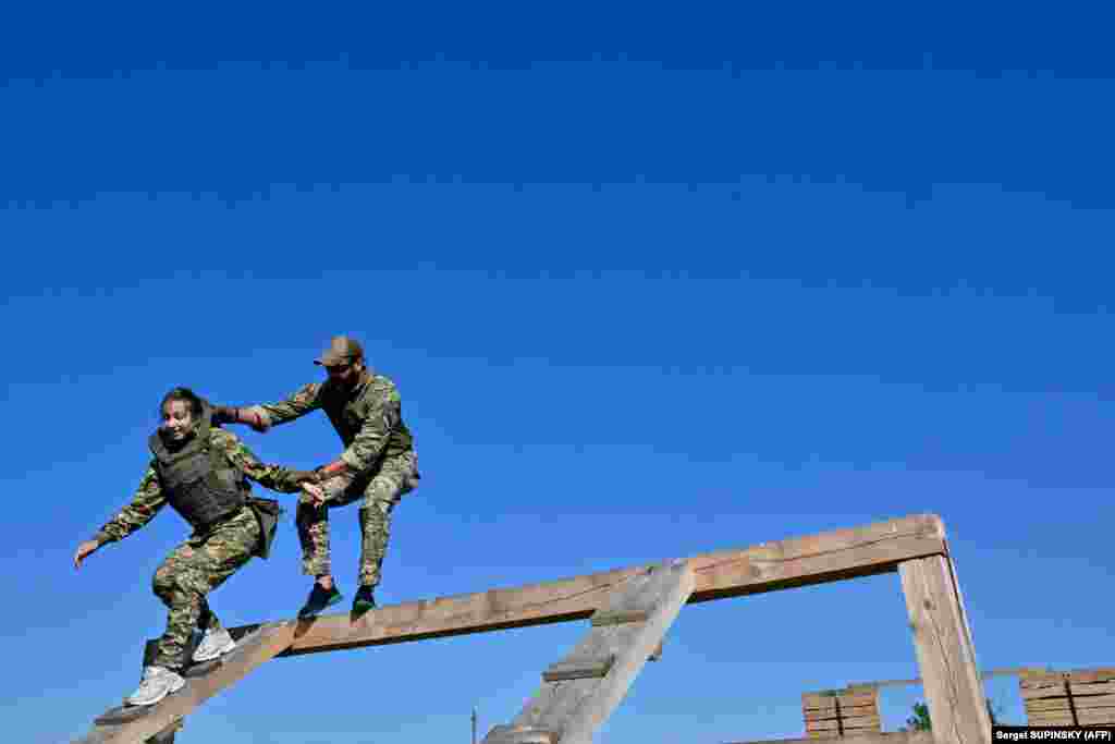 An instructor helps a cadet wearing the new military uniform run through an obstacle course at the training ground outside Kyiv.
