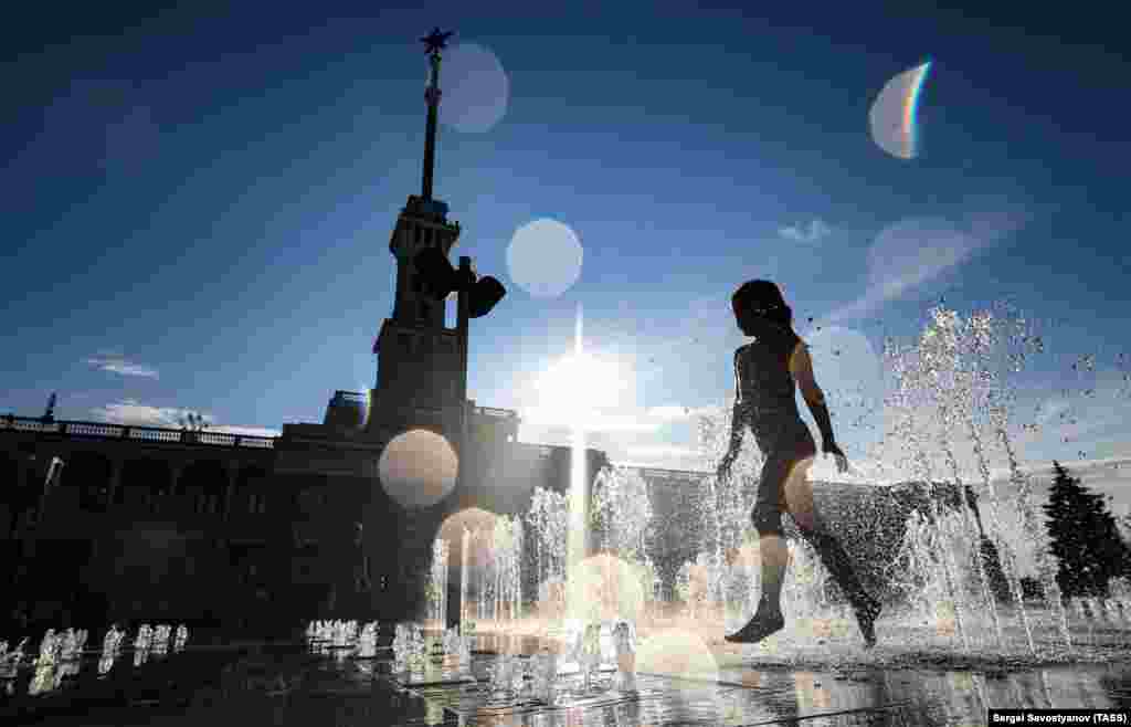A girl plays with water in a fountain during hot weather in Moscow.&nbsp;