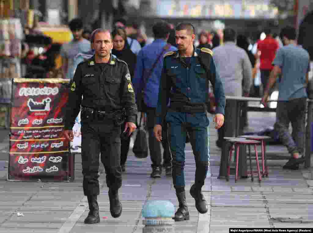 Two policemen walk through Tehran on July 16. The officer on the left is wearing the standard green uniform&nbsp;that is worn&nbsp;by units of the morality police. &nbsp;