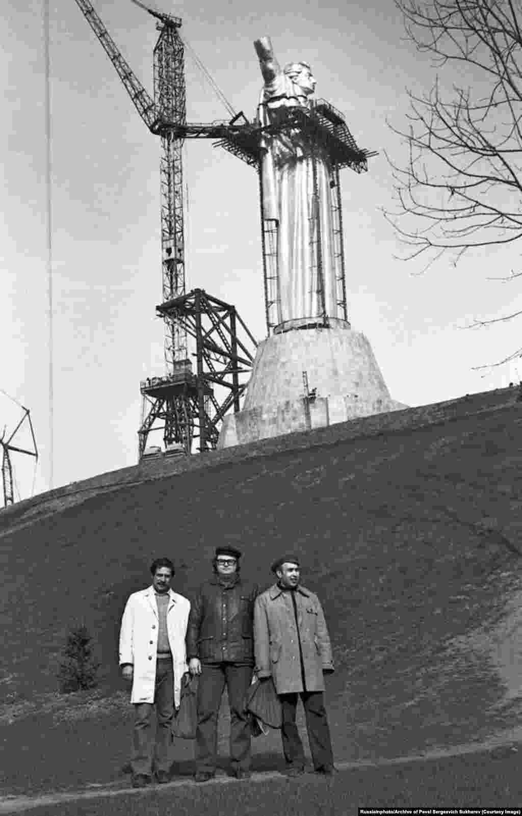 Men posing in front of the Motherland Monument during its assembly in March 1981. Construction of the steel-skinned statue began in 1979 and was completed in 1981.