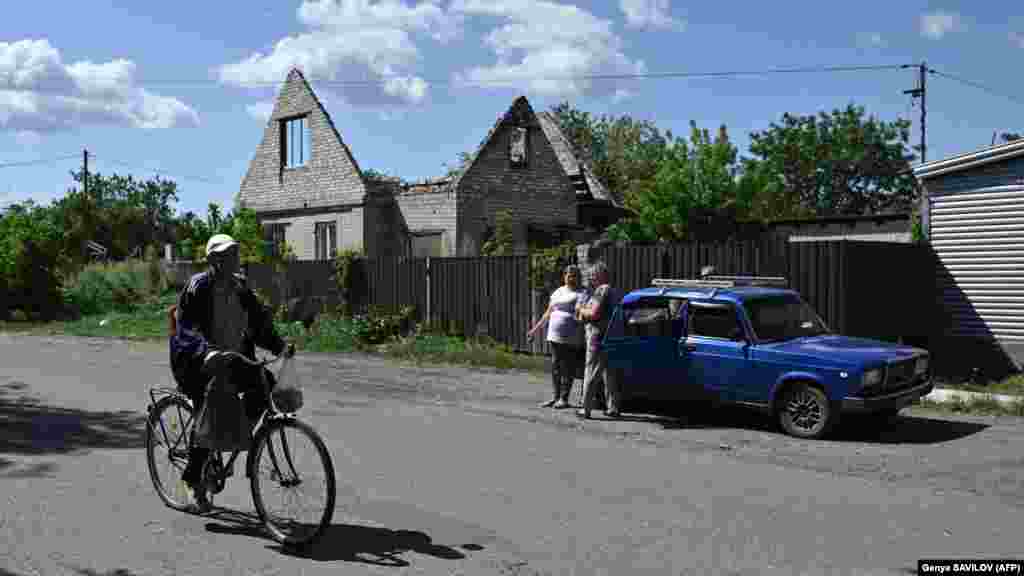 A resident rides a bicycle past a heavily damaged building on a street in the town of Lyman.&nbsp; The eastern Ukrainian town continues to be targeted with Russian rockets that maim and kill its civilians. &nbsp;