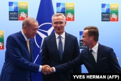 Erdogan and Swedish Prime Minister Ulf Kristersson shake hands next to NATO Secretary-General Jens Stoltenberg prior to their meeting on the eve of the NATO summit in Vilnius on July 10.