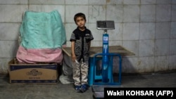 An Afghan boy stands besides a scale while waiting for customers at an underground passageway in Kabul on June 27.<br />
<br />
Traders in Afghanistan are struggling with sales as the three-day&nbsp;Muslim festival Eid al-Adha, or Festival of Sacrifice, begins on June 28.&nbsp;