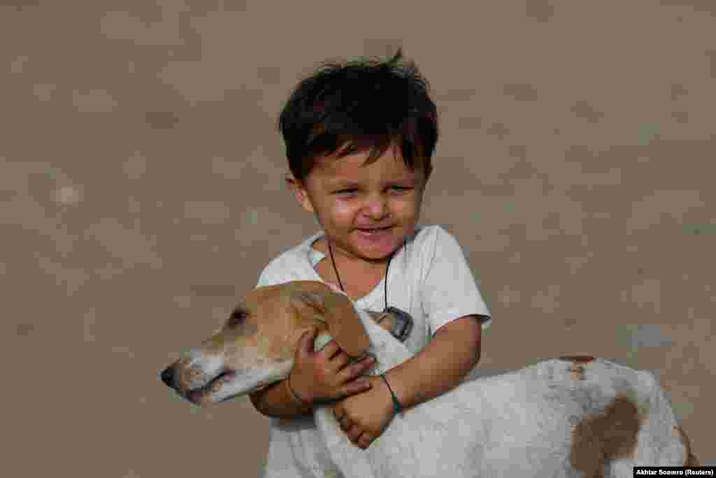 Shahyan, 2, plays with his family&#39;s pet dog, Moti, in a slum area of Karachi.