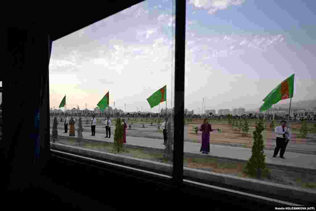 Another picture taken from inside the media bus shows participants holding Turkmen flags along the route toward the new city.&nbsp;&nbsp; The elder Berdymukhammedov ran the gas-rich desert nation of 6 million for 15 years until 2022. He became the center of an elaborate -- and sometimes bizarre -- personality cult.&nbsp;