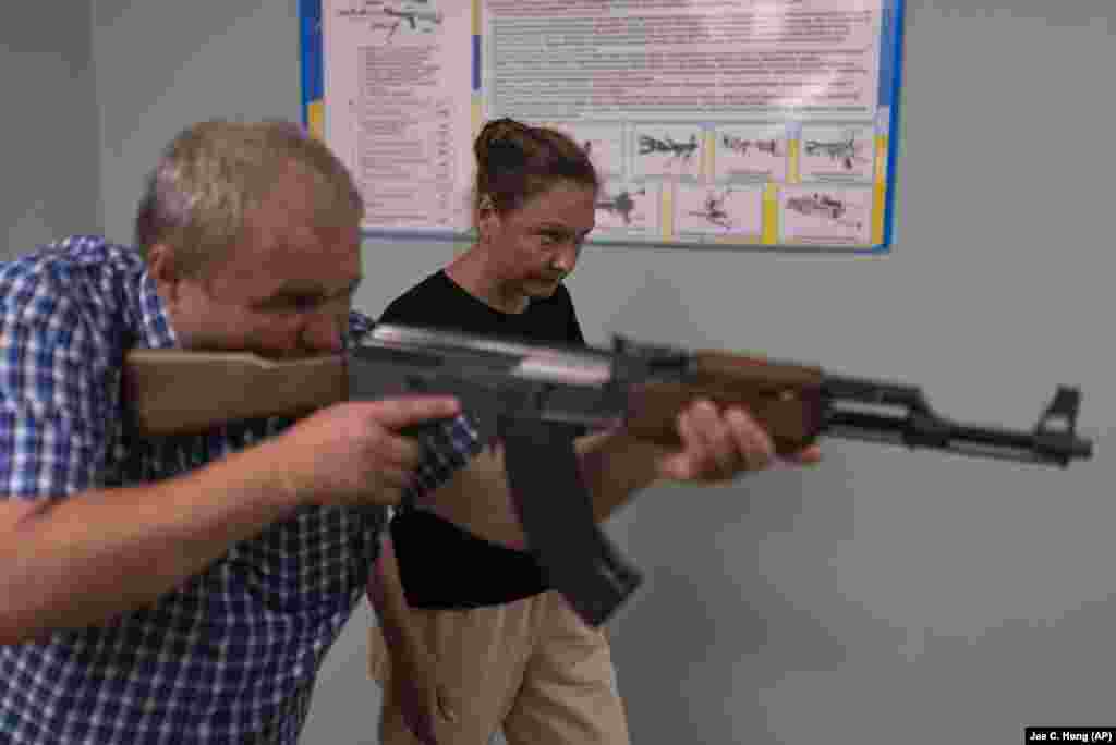 Instructor Oleksiy Ogirenko shows Iryna Chudna how to aim a rifle during firearms training. &nbsp;