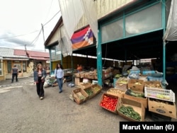 Locals of Stepanakert walk past vegetables for sale on July 18. Locally grown produce is being sold for several times usual prices locals say, putting them out of reach for many people.