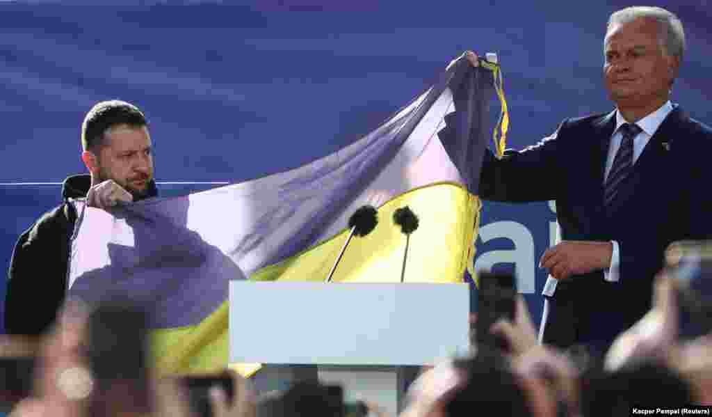 Ukrainian President Volodymyr Zelenskiy and Lithuanian President Gitanas Nauseda hold a Ukrainian flag from the front line of the war with Russia, on the sidelines of a NATO leaders summit in Vilnius.