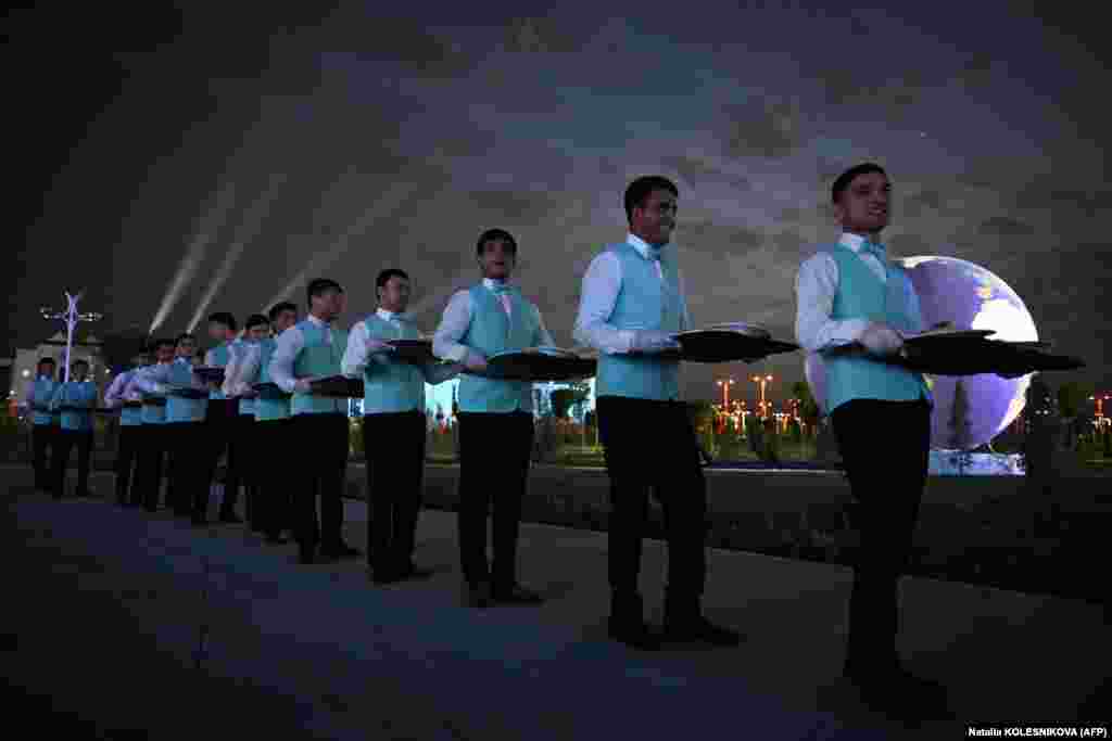 Waiters holding trays wait to bring out the food for guests during the evening festivities.&nbsp;