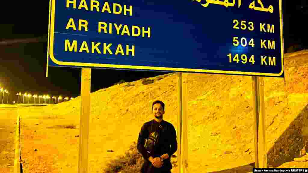 A smiling Arshad underneath a highway sign in Al-Batha, Saudi Arabia. For pilgrims, the journey allows time for reflection that brings them closer to God and a sense of community, especially when people from many backgrounds join together. &nbsp;