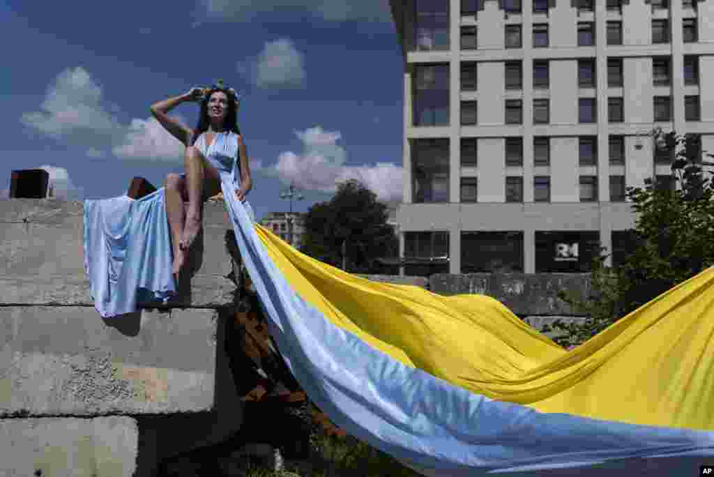 Dressed in the colors of the Ukrainian flag, Maria Berdiyeva poses for photos to help raise money for Ukrainian troops in Kyiv on July 10.
