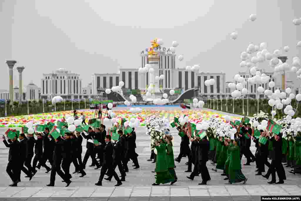 Participants parade with Turkmen flags, artificial flowers, and white balloons during the ceremony.&nbsp; &nbsp;