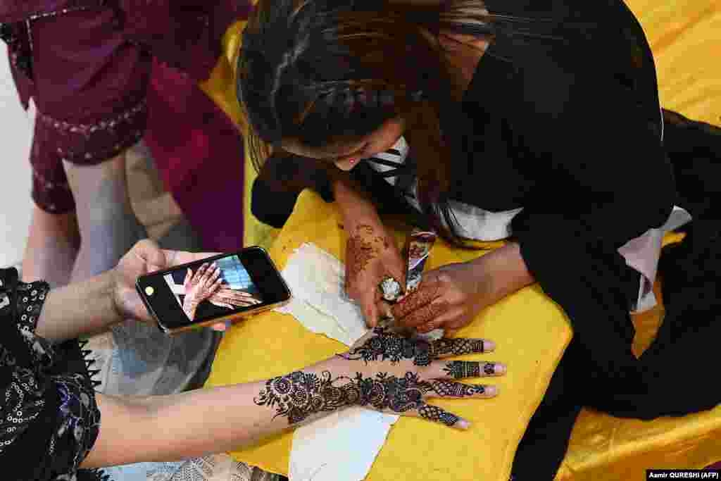 A beautician applies henna to a customer&#39;s hand in Islamabad ahead of the Eid al-Fitr festival.