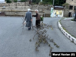 Elderly women in Stepanakert on the evening of July 17. One of the women is dragging a branch she will use for firewood to cook with.
