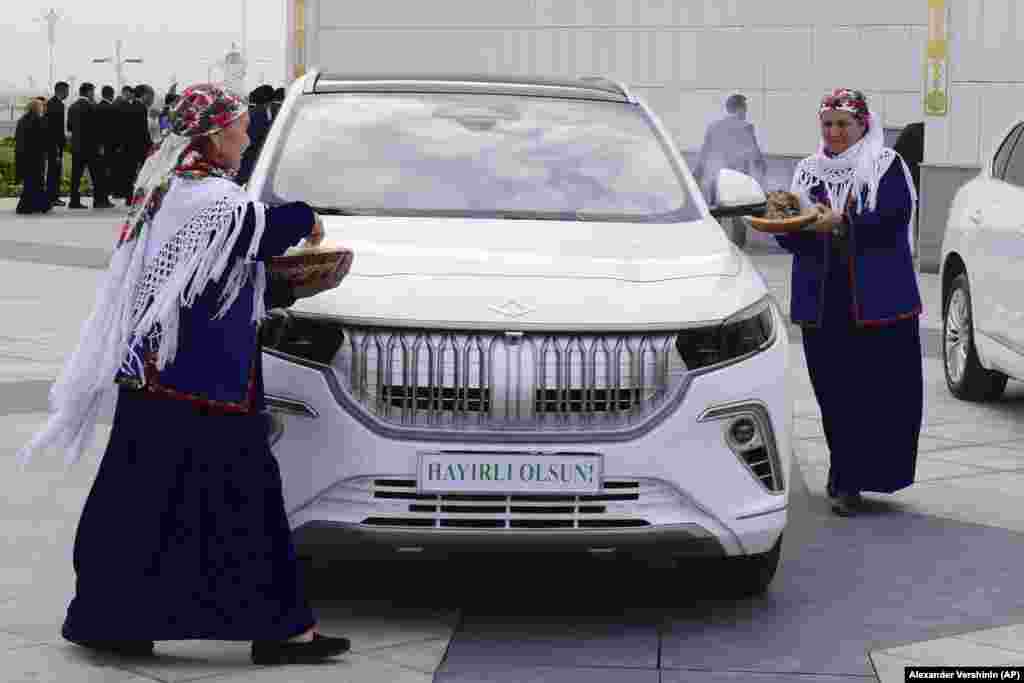 Women wearing national Turkmen clothes sprinkle flour on electric cars donated by Turkish President Recep Tayyip Erdogan. The ritual is supposed to bring longevity. The vehicles were also fumigated with smoke, which, according to legend, drives away evil spirits.
