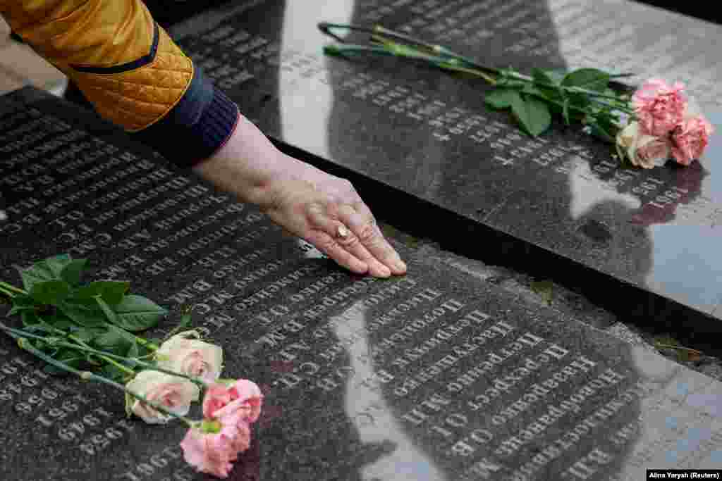 A woman touches the name of a Chernobyl victim at the Kyiv monument.