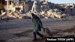 An elderly woman pulls a trolley bag past a destroyed building in Bakhmut in Ukraine's Donetsk region in December 2022. 