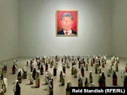 A portrait that mashes Chinese President Xi Jinping and Russian President Vladimir Putin is displayed in a Badiucao exhibition at the DOX Center for Contemporary Art in Prague in May 2022. Molotov cocktails in soy sauce bottles are on the floor.