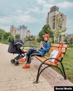 A 2019 photo of Iryna relaxing in a park in southern Kyiv as her daughter sleeps in a pram with white-rimmed wheels.
