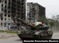 A tank manned by Russia-backed separatists drives through the streets of Popasna in May 2022.