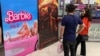 Moviegoers stand in front of the poster for the movie Barbie at a cineplex in Islamabad on July 21.