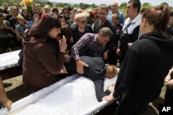 Oleg Aksenchenko cries over the coffins of his 14-year-old twin daughters Anna and Yuliia, who were killed by a Russian rocket attack on a pizza restaurant in Kramatorsk, during their funeral ceremony on June 30.