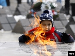 A Romanian child, a relative of a victim of the revolution, looks at an eternal flame at a commemorative event in Timisoara in December 2009.