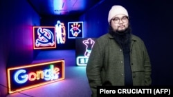 Chinese dissident artist Badiucao poses next to his neon lights artworks series on Hong Kong, in November 2021 at his exhibition in Brescia, Italy.